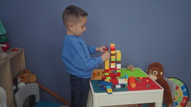 Hispanic boy carefully stacking colorful plastic blocks with hands into a tall tower on a play table in building; quiet concentration.