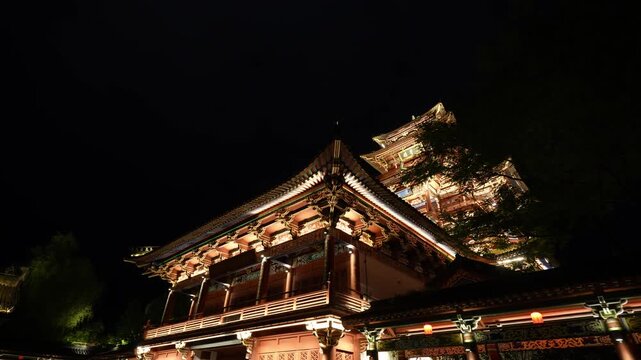 Traditional Chinese temple with flying eaves and dougong brackets illuminated by warm night lighting
