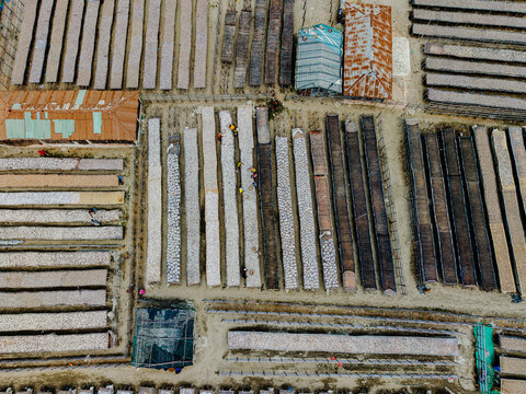 Cox's Bazar, Bangladesh - 11 March 2026: Aerial view of a traditional fish drying yard with workers tending to long rows of fish on racks.