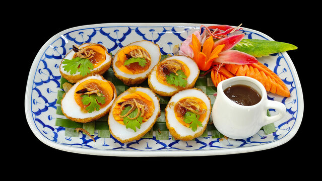 Elegant Thai appetizer of deep-fried hard-boiled eggs with savory tamarind glaze, perfect  on black background.