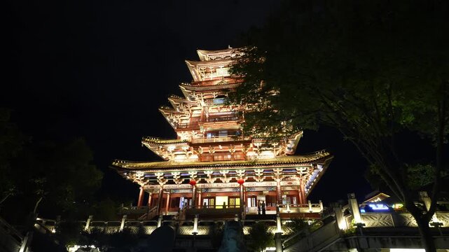 Illuminated multi-tiered traditional Chinese pavilion at night with intricate architectural details