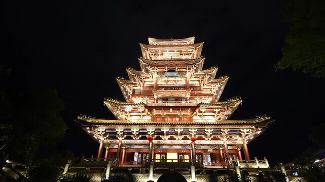 Multi-tiered traditional Chinese pagoda illuminated by night lighting with ornate eaves and wooden architecture