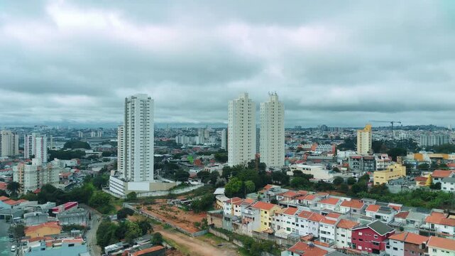 Vista a&eacute;rea urbana com pr&eacute;dios residenciais e c&eacute;u nublado, ideal para conte&uacute;do urbano e imobili&aacute;rio.