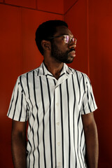 Fototapeta premium Black man standing against red wall contemplating
