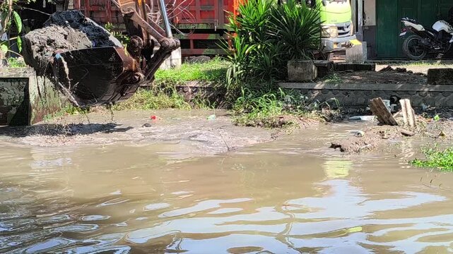 Heavy excavator dredging a river to remove sediment and improve water flow, showcasing large construction equipment working on river maintenance and flood prevention in daylight