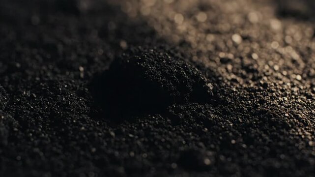 Close-up macro shot of dark fertile soil with small pebbles and granular texture, highlighting earth's natural