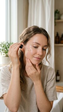 Woman applying facial serum with dropper for skincare routine