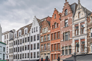 Fototapeta premium A row of traditional buildings in Antwerp displays the citys rich architectural heritage, with historic facades aligned along a charming street beneath a cloudy sky.
