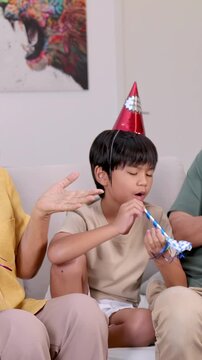 Asian Boy Blowing Party Horn at Family Birthday Celebration
