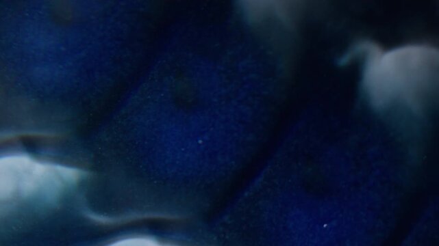 Paint splotch defocused. Art fluid. Blue drop mixing with gray fluid on dirty background. Prism lens abstract color flow optical effect.
