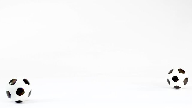 Two Miniature Soccer Balls Rolling and Bouncing on White Background