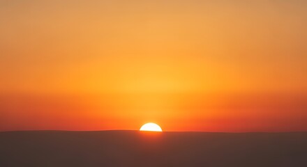 Fototapeta premium Sunset over horizon with setting sun in warm orange sky