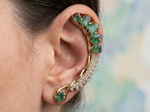 Elegant ear cuff with green gemstones and diamonds on a woman's ear
