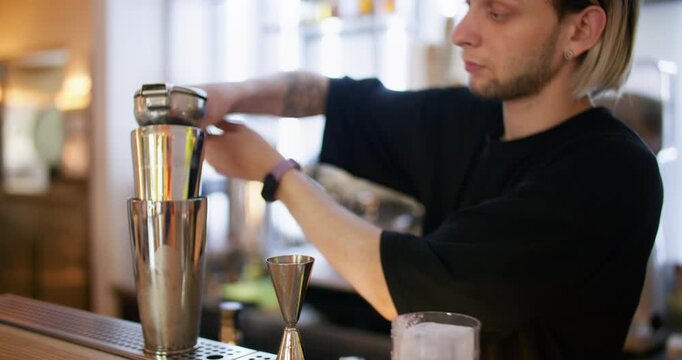 Drink preparing. Bar service. Barkeeper squeezing fresh citrus juice with professional tool pouring aroma liquid in metal cocktail shaker.