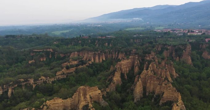 Aerial view of the Balze del Valdarno rock formations with unique clay pinnacles and dense green vegetation in Castelfranco Piandisco, Tuscany, Italy.