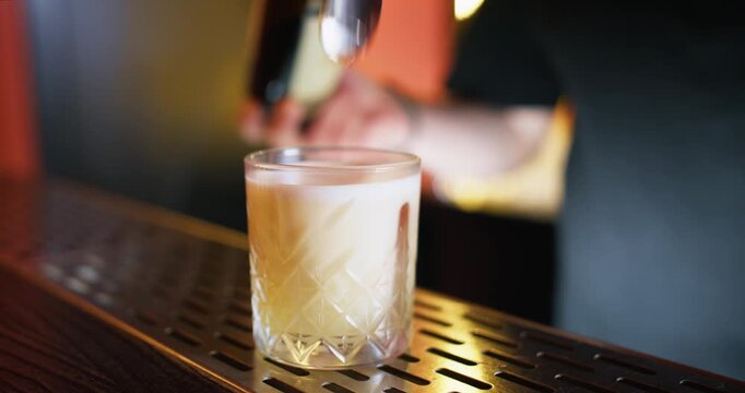 Alcohol cocktail. Syrup beverage. Unrecognizable barman hands pouring liquid using professional spoon in transparent glass on bar counter.