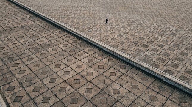 Man Walking On Large Geometric Pattern Stone Plaza Diagonal Composition Minimal 154