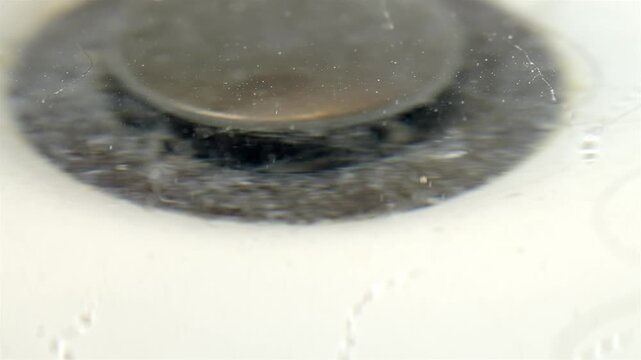 Blurry close up of a dirty bathtub drain with hair and flowing water