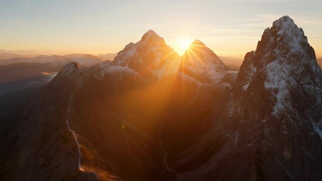 Mountain peaks at golden sunset with sunbeams illuminating snowy ridges snow-covered