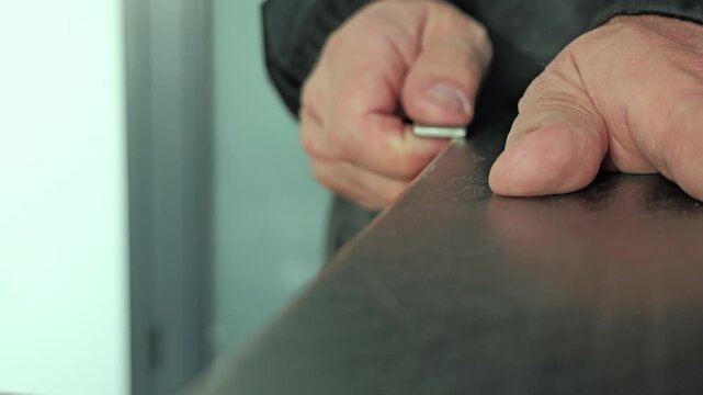 Close up video shows hands using diamond sharpening tool on ski edge, performing precise maintenance and smoothing of metal surface in workshop setting 2026