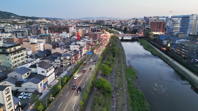 Kyoto aerial view of Kamo River and city buildings. Golden hour panorama with riverside temples traditional rooftops glowing