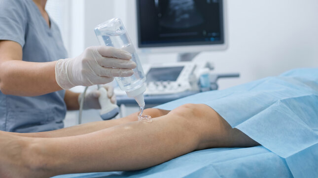 Doctor performs focused ultrasound examination on patient leg. This medical diagnostic procedure in modern clinic checks vein using advanced equipment for health screening