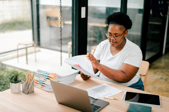 Black woman organizing documents at office desk