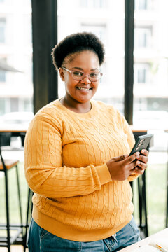 Smiling black woman holding smartphone communicating online