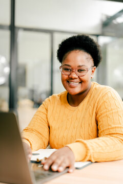 Happy young woman working on laptop in modern office