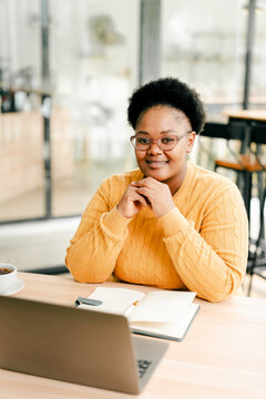Smiling black woman working on laptop at cafe