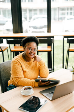 Young woman studying at cafe with digital devices