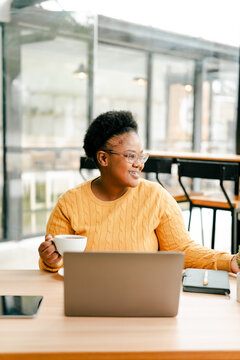 Black woman smiling working on laptop in cafe