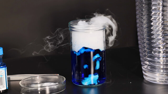 Dry Ice Sublimating in Blue Liquid Inside a Glass Laboratory Jar