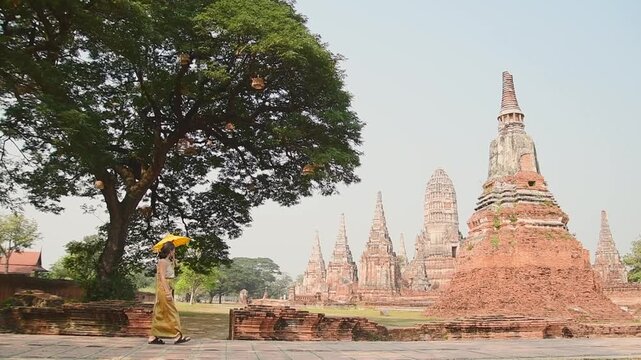 Thailand, Ayutthaya - march 15th, 2023: Woman in traditional Thai dress pose sightseeing visit ancient Buddha statue.Ayutthaya historical park. UNESCO World Heritage Site