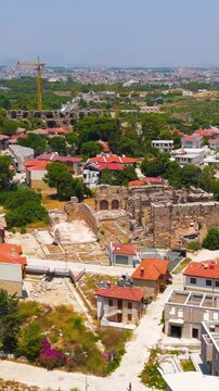 Vertical video. Side, Manavgat, Turkey. Aerial view of ancient great hammam ruins and modern city, Ottoman bath complex on Mediterranean coast summer day. Aerial View. Rich colors