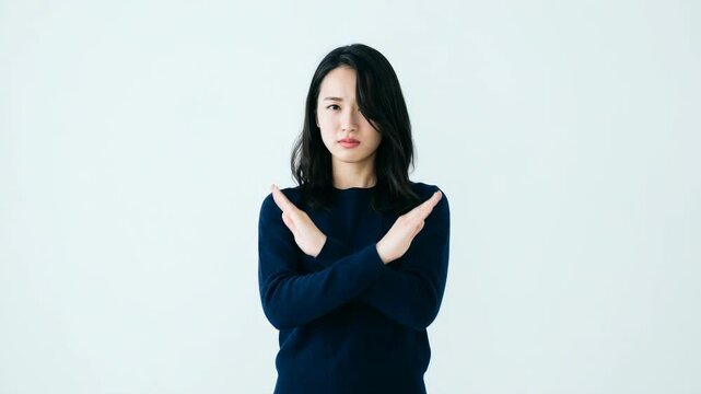Asian woman making X sign with crossed arms to express rejection refusal or stop gesture for negative concepts on white background
