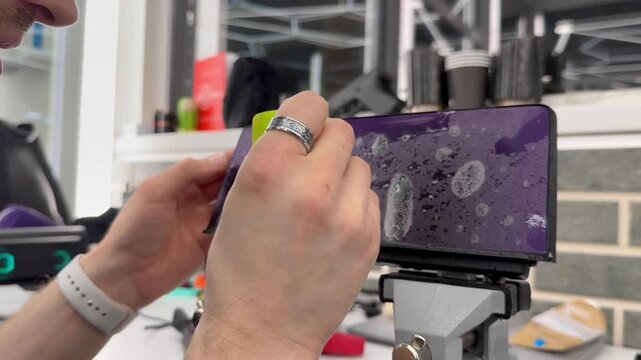 A man wrapping a protective PPF film on a car monitor. The protective glass or film protects the monitor from scratches, fingerprints, other mechanical damage. Wrapping a PPF film to the car display. 