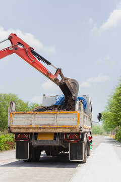 An orange crawler excavator digs a paved residential road for maintenance.