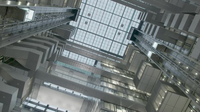 Looking up at modern glass elevators and geometric architecture inside a bright atrium