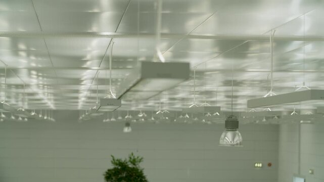 Modern suspended ceiling lights in bright commercial interior, focus on fixtures