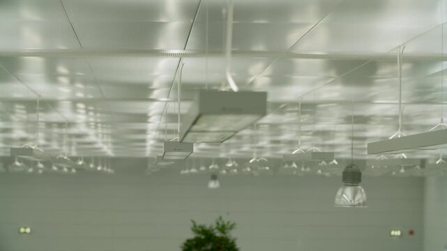 Modern ceiling lights in office interior with reflection on metallic grid ceiling panels