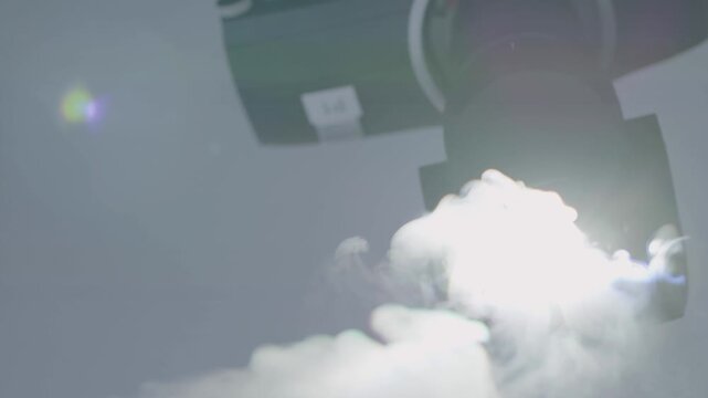 Automated stage light turns on and emits fog in a controlled indoor studio setting