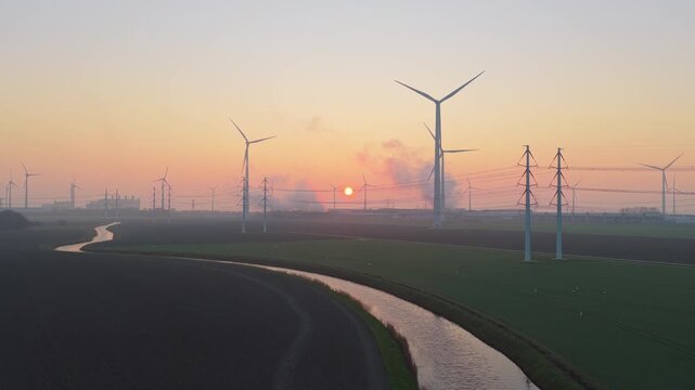 Aerial view of the google data center in eemshaven, netherlands, with its cooling systems and nearby wind farm during a hazy sunrise