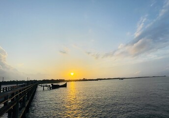Obraz premium sunset over the sea. Golden Sunset Seascape with Traditional Wooden Boat and Bridge, Tranquil Coastal Mood.