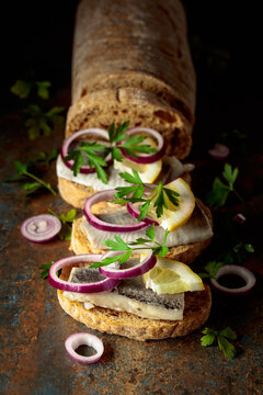 Open sandwiches with herring filet, red onion, lemon, and parsley.