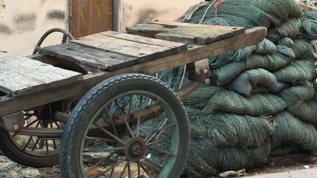 Close-Up of Old Wooden motorbike Cart and Large Pile of stacked Green Fishing Nets 