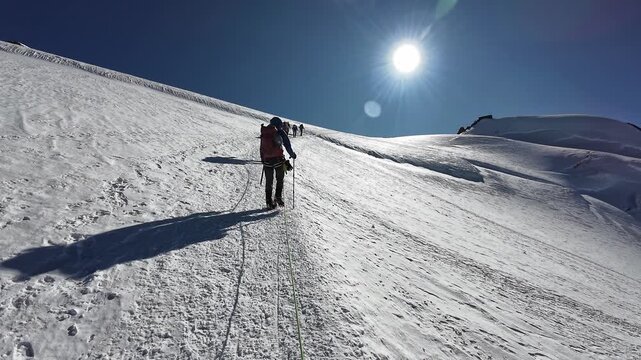 POV mountaineering in rope team with mountaineers ascending towards summit Signalkuppe with mountain hut Margherita Hut and glacier panorama of Monte Rosa massif in Pennine Alps, Italy
