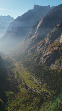 Aerial view of Val di Mello valley with steep granite cliffs, green meadows and a winding stream, Val Masino, Lombardia, Italy.