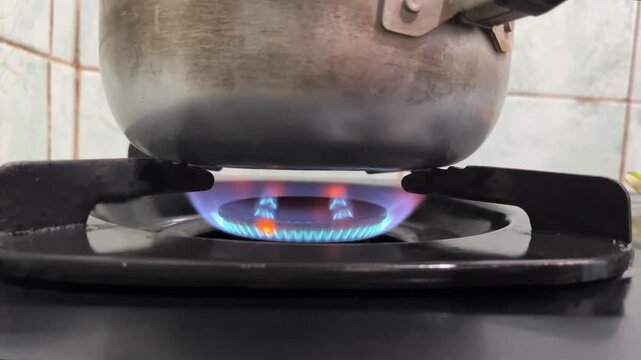 Blue gas flame burning from a stove burner under a cooking pot