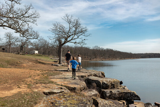 Father and sons walking together on a rocky path by a large lake